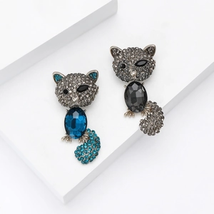 Fashionable cat brooches with faceted gemstones and rhinestones on white platform