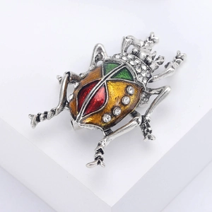 Macro detail of vintage beetle brooch with colorful enamel wings and sparkling rhinestones