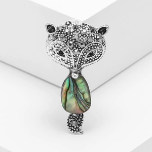 Retro fox brooch with abalone shell inlay and black rhinestones on a white stand