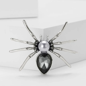 Macro shot of spider brooch with grey pearl body and teardrop-shaped gemstone detail