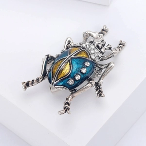 Macro detail of vintage silver beetle brooch with blue enamel and sparkling crystals