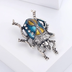 Detail showing beetle brooch with blue and yellow enamel inlay and sparkling crystals