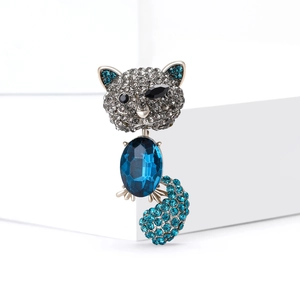 Elegant cat brooch with blue crystals and sparkling rhinestones on a white pedestal