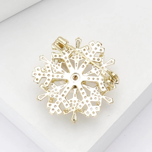 Detail of the rotating three-layer snowflake brooch with gold finish and zircon inlay
