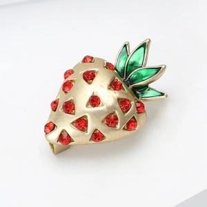 Détail de la broche fraise avec strass rouges et feuilles en émail vert élégantes