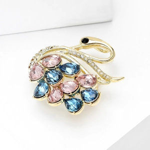 Macro shot of luxury crystal swan brooch with pink and blue pear-cut zircons on gold base