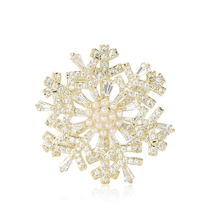 Luxury rotating gold snowflake brooch with pearls and cubic zirconia on white background