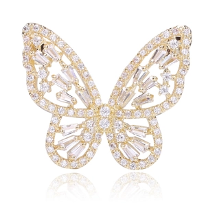Détail d'une broche papillon évidée dorée avec des pierres de zircon rondes et rectangulaires