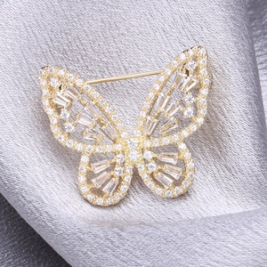 Gros plan d'une broche papillon dorée avec zircons étincelants sur tissu de soie