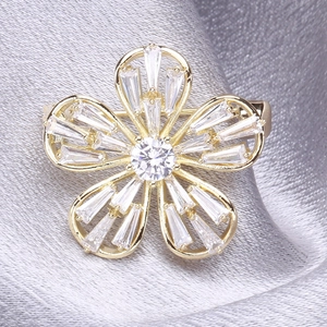Broche fleur dorée élégante avec oxydes de zirconium sur fond en satin argenté