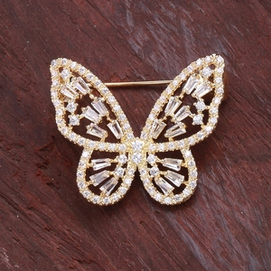 Broche papillon étincelante en or avec zircons blancs sur fond en bois