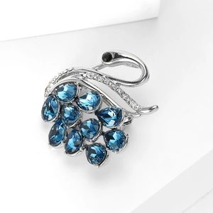 Macro shot of silver swan brooch featuring dark blue teardrop crystals and fine micro-pave
