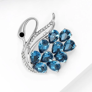 Detail of luxury swan brooch with blue pear-cut crystals and sparkling zircons