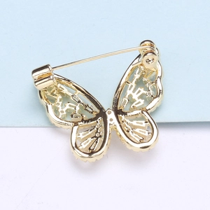 Vue arrière détaillée d'une broche papillon dorée avec ailes ajourées et épingle