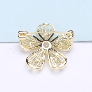 Détail du revers d'une broche fleur dorée à cinq pétales avec épingle et motif ajouré