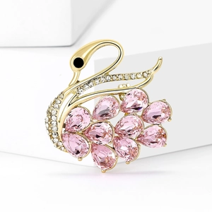 Detailed close-up of a crystal swan brooch with pink stones and zircons on white steps