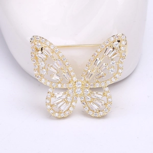 Gros plan d'une broche papillon dorée avec des ailes ajourées et des zircons blancs