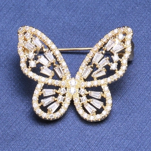 Élégante broche papillon dorée avec strass blancs étincelants sur tissu bleu foncé