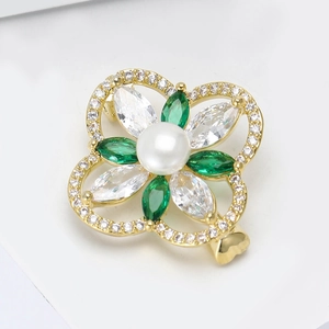 Eleganter Kleeblatt-Anstecker aus Gold mit grünen Zirkonen und einer weißen Perle auf Weiß