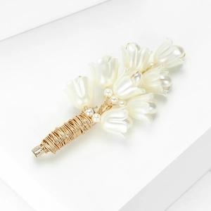 Close-up of handmade lily of the valley brooch with white pearls and gold wire details