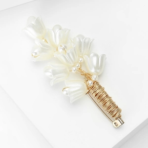 Macro shot of lily of the valley brooch with pearlescent petals and gold woven stems