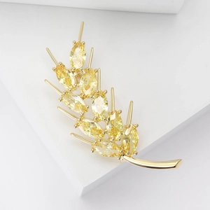 Elegant gold wheat ear brooch with sparkling yellow zircon stones on white background