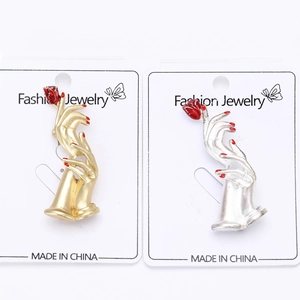 Close-up of gold and silver hand-held red rose brooches on fashion jewelry cards
