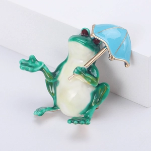 Gros plan d'une broche grenouille avec parapluie bleu, détails en émail et placage doré