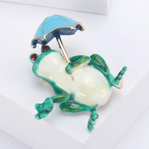 Détail d'une broche grenouille verte tenant un parapluie bleu clair à bord doré