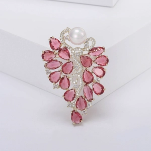 Détail de broche fleur de luxe avec zircons rouge vin, perle blanche et monture dorée