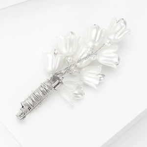 Detail of handcrafted lily of the valley brooch with pearl white petals and silver wire