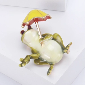 Détail d'une broche grenouille mignonne avec parapluie jaune sur fond blanc épuré
