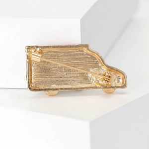 Revers d'une broche ambulance dorée montrant le fermoir épingle et le métal texturé
