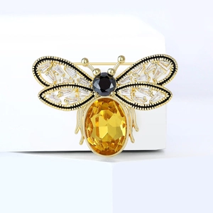 Broche abeille dorée luxueuse avec pierre jaune et cristaux sur plate-forme blanche
