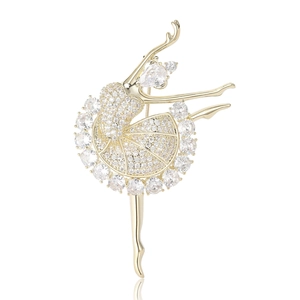 Broche ballerine dorée élégante ornée de cristaux scintillants sur fond blanc