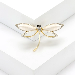 Detailed close-up of golden dragonfly brooch featuring opal wings and pavé crystals