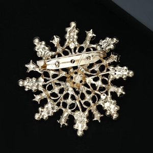 Close-up of the golden snowflake brooch back showing detailed hollow craftsmanship and safety pin