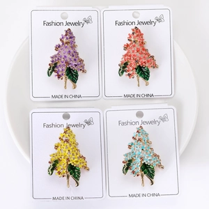 Detail of four colorful enamel hydrangea brooches in purple, orange, yellow and blue colors