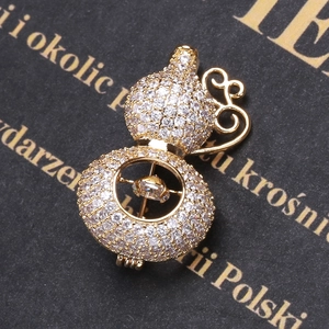 Detail of a luxury gold gourd brooch with micro-pave zircons and dancing center stone