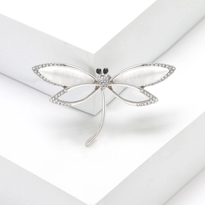 Elegant dragonfly brooch with cat eye stone and sparkling crystals on a modern white base