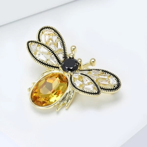 Détail macro d'une broche abeille dorée avec ambre et ailes ornées de zircons