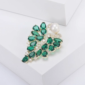 Détail de la broche fleur vintage avec pierres d'émeraude et perle blanche centrale