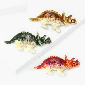 Trois jolies épingles émaillées Tricératops en marron, vert et orange sur fond blanc épuré