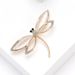 Elegant gold dragonfly brooch with opal wings and sparkling crystals on a white stand