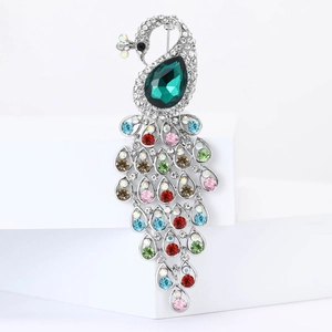 Elegant peacock brooch with green pear-shaped stone and colorful rhinestones on white stand