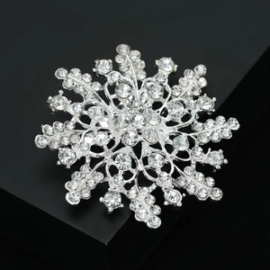 Macro shot of silver snowflake brooch with sparkling rhinestones on black display