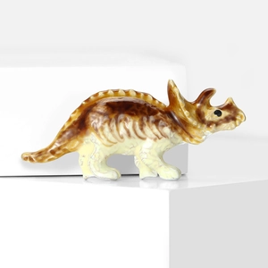 Détail macro d'une broche tricératops en céramique sur un support blanc épuré