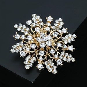 Close-up of golden alloy flower brooch with sparkling rhinestones on a black background