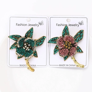 Detailed macro view of emerald and purple rhinestone flower brooches on display cards
