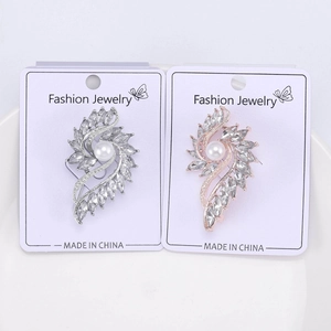 Close-up of swirling silver and rose gold brooches with sparkling crystals and large pearls
